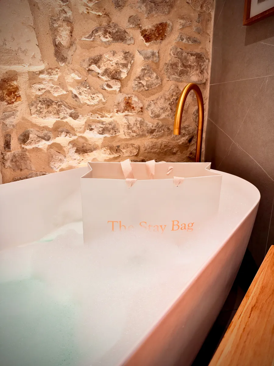 The Stay Bag posé dans une baignoire remplie de mousse, contre un mur en pierre