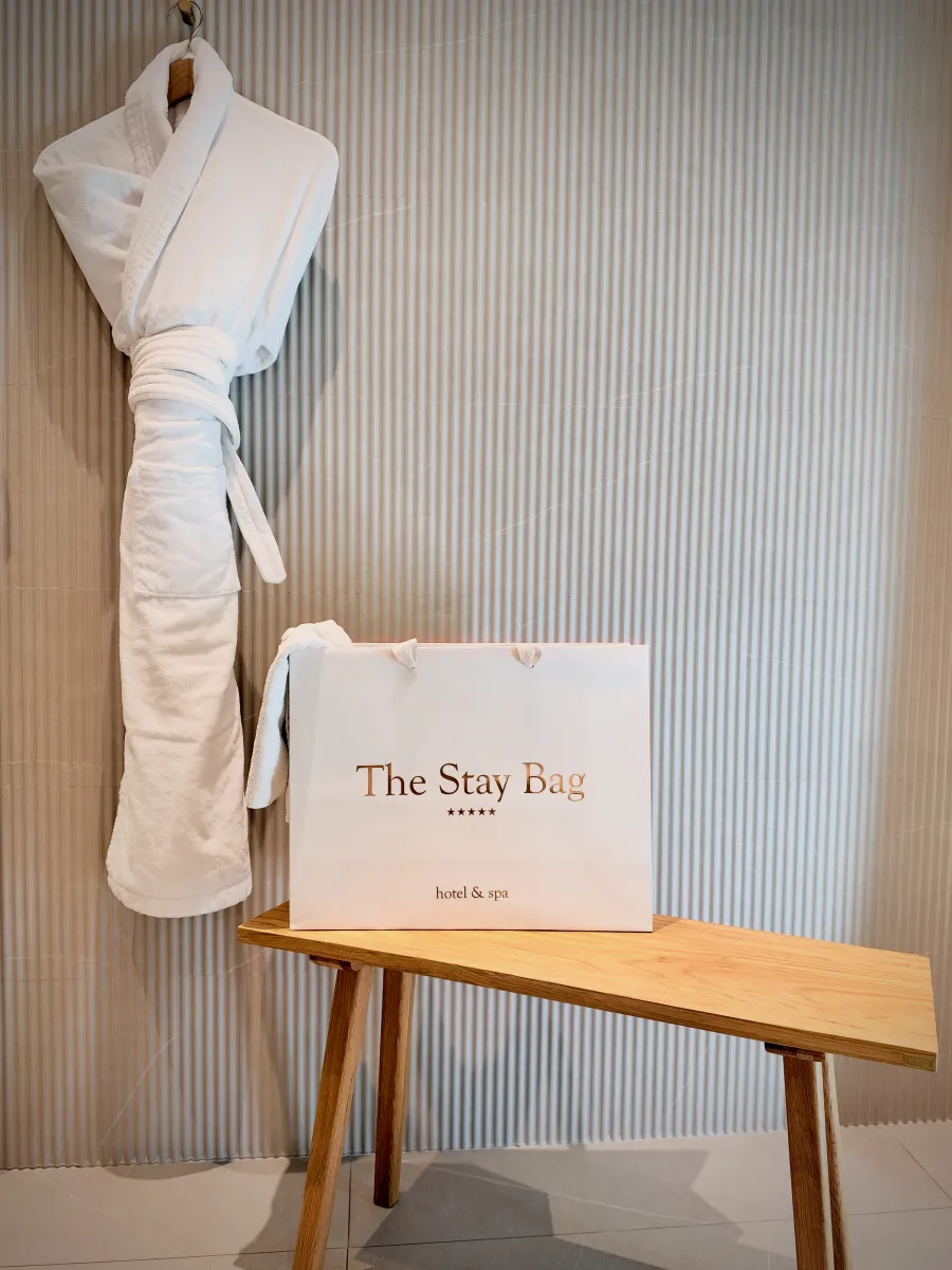 The Stay Bag posé sur un banc de chambre, sous un peignoir suspendu