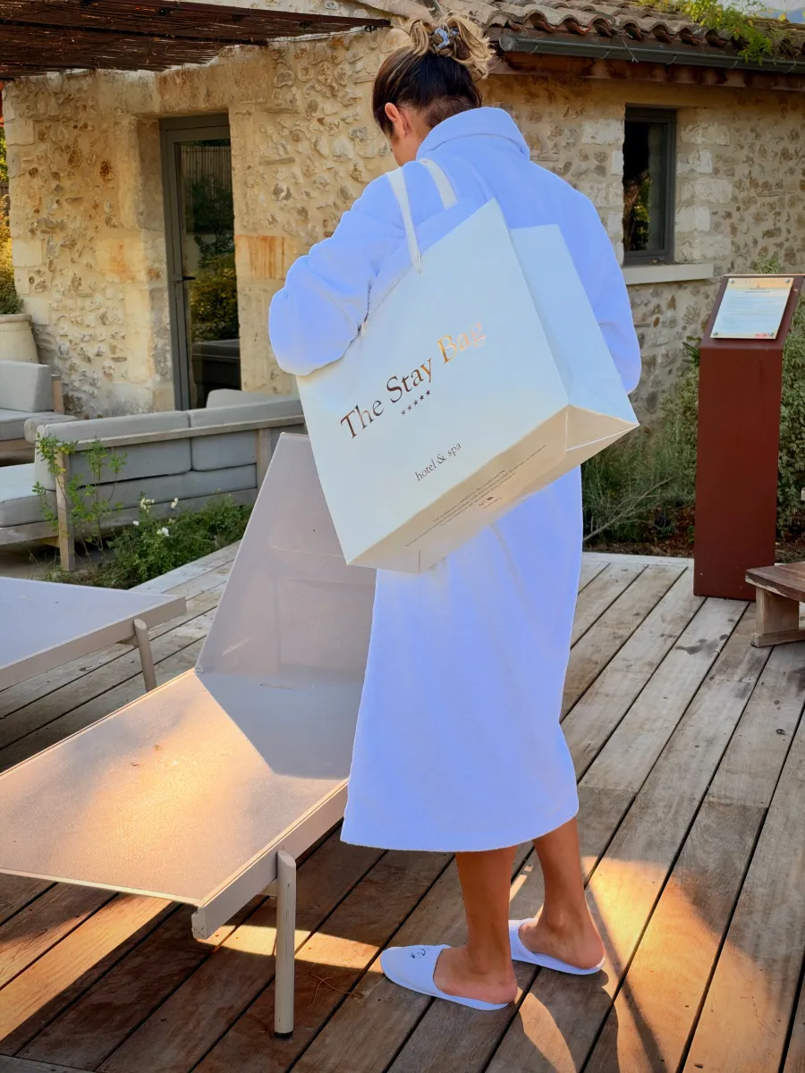 Cliente en peignoir, The Stay Bag à l'épaule, sur la terrasse du spa