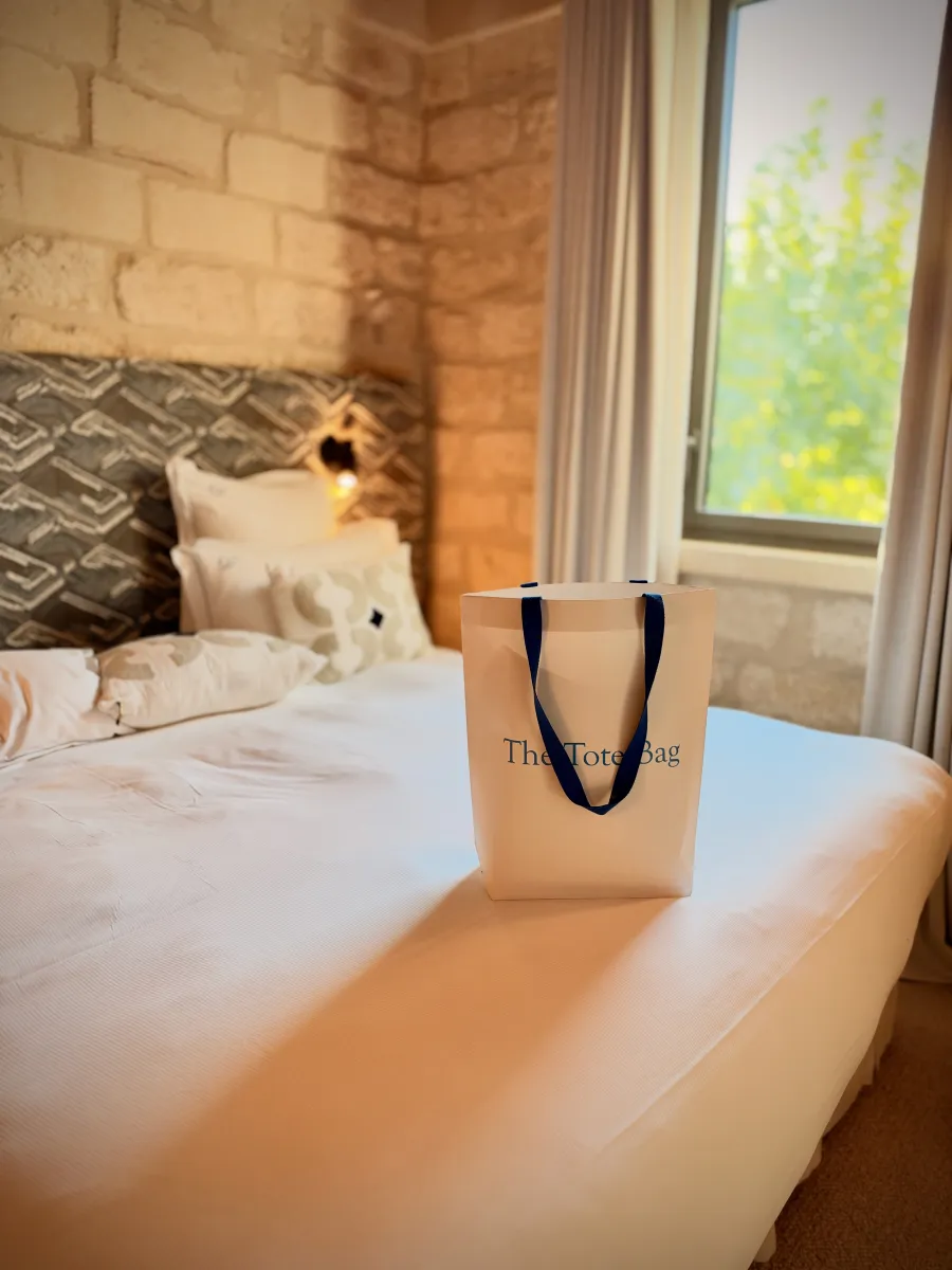 The Tote Bag debout sur le lit d'une chambre en pierre